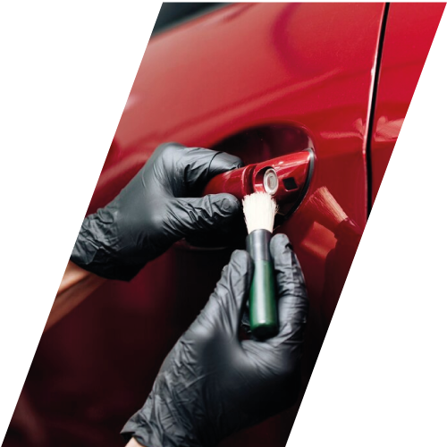Persona con guantes limpiando la cerradura de un vehículo rojo con un pincel